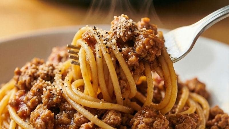 Gros plan sur une fourchette de spaghettis enrobés d'une sauce bolognaise vegan aux protéines de soja texturées.
