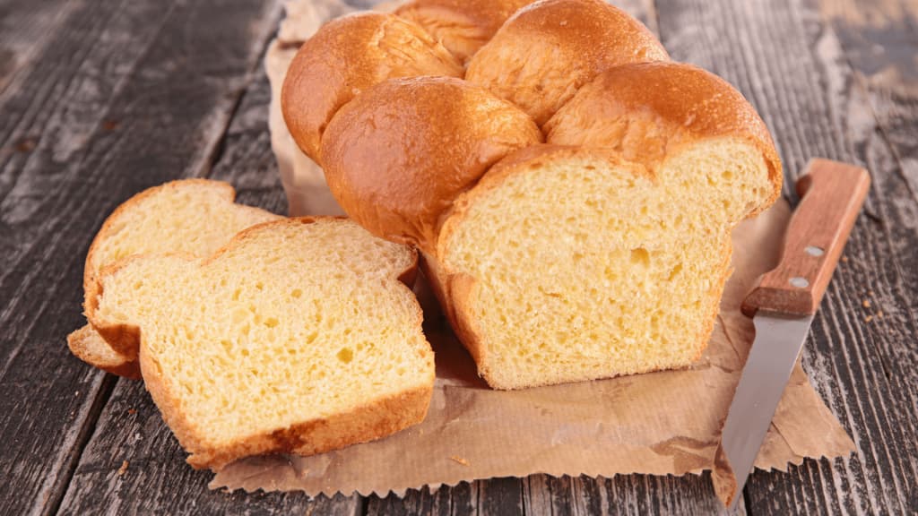 Une superbe brioche vegan sur un table en bois coupée avec un couteau