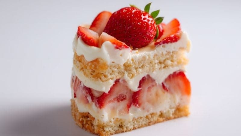 Une part de Fraisier Vegan découpée avec de la crème et des fraises entières