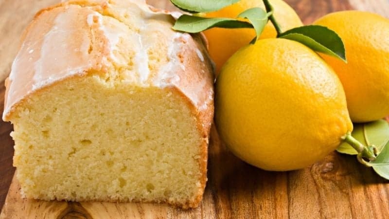 Un cake au citron vegan sur une planche en bois avec des citrons entier