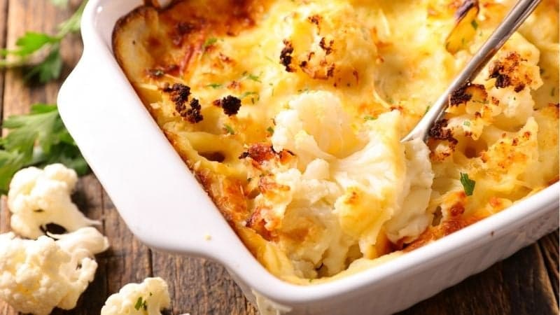 Un gratin de chou-fleur vegan lors d'un repas de famille sur une table en bois