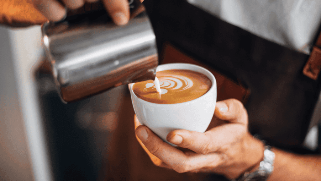 Un serveur qui prépare un café avec le meilleur lait végétal pour café