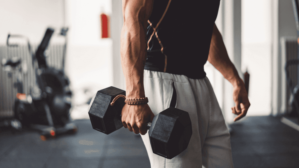 Un homme en pleine séance de musculation avec un débardeur noir et une haltère