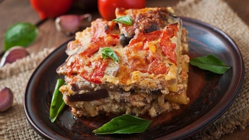 Une part de moussaka vegan lors d'un diner de famille sur une belle assiette marron