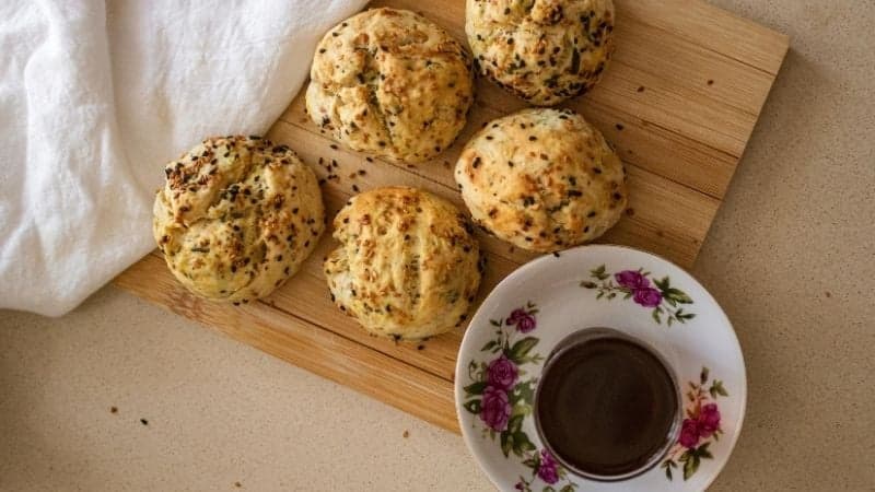 5 scones vegan posés sur une planche en bois avec une tasse de thé pour un moment entre amies